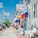 Cars line the sidewalk of a shopping district with low rise A frame buildings in a small town
